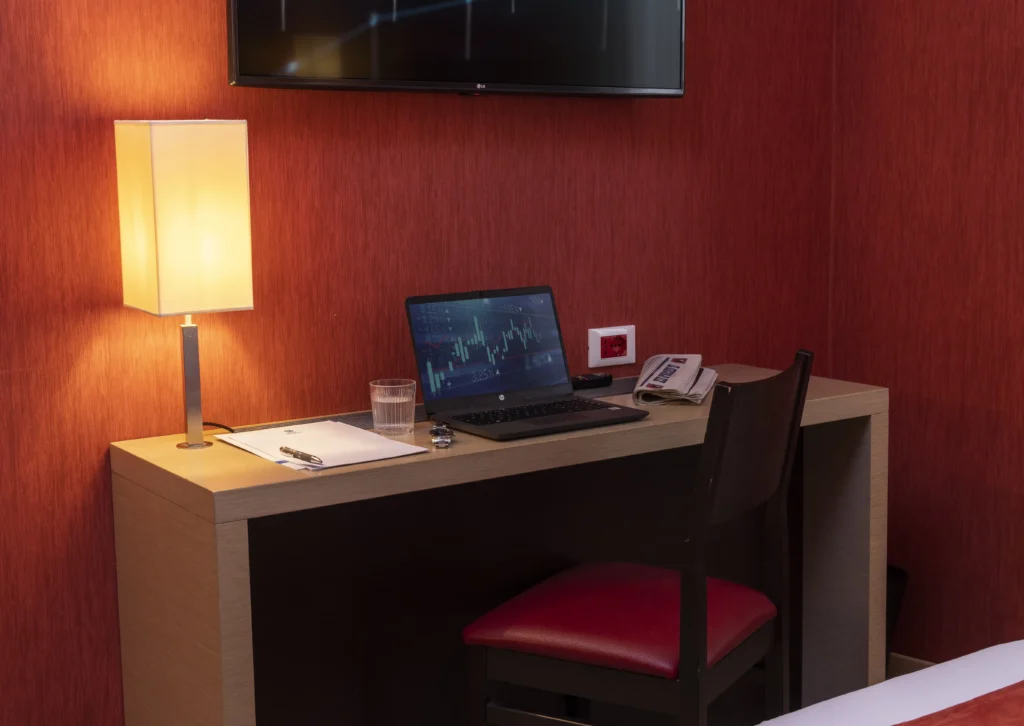 Nell'immagine una camera con un letto matrimoniale e una scrivania con sopra un pc